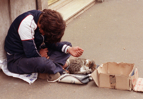 Un ragazzino chiede l'elemosina in compagnia di un gattino in una foto di archivio scattata a Roma © ANSA