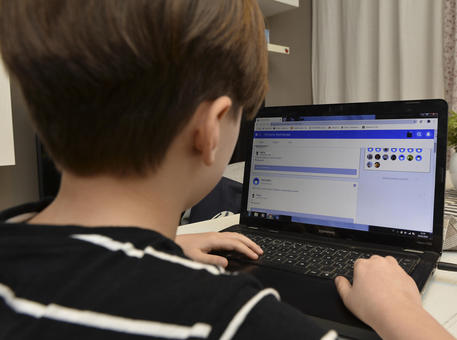 Uno studente della Scuola Elementare Renzo Pezzani di Milano svolge alcuni compiti  online organizzati dall'insegnante © ANSA