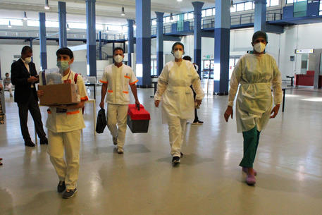Operatori sanitari indossano tute e mascherine protettive per effettuare controlli © 