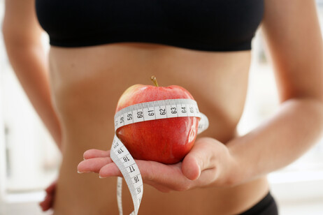 Una giovane donna magra con una mela in mano, un simbolo delle diete estreme foto iStock.