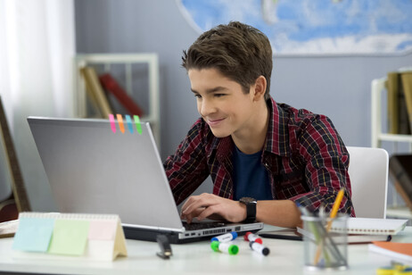 Un giovane adolescente con un computer aperto foto iStock.