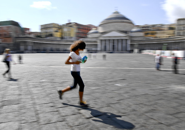 Una ragazza corre in Piazza del Plebiscito a Napoli con la mascherina © ANSA