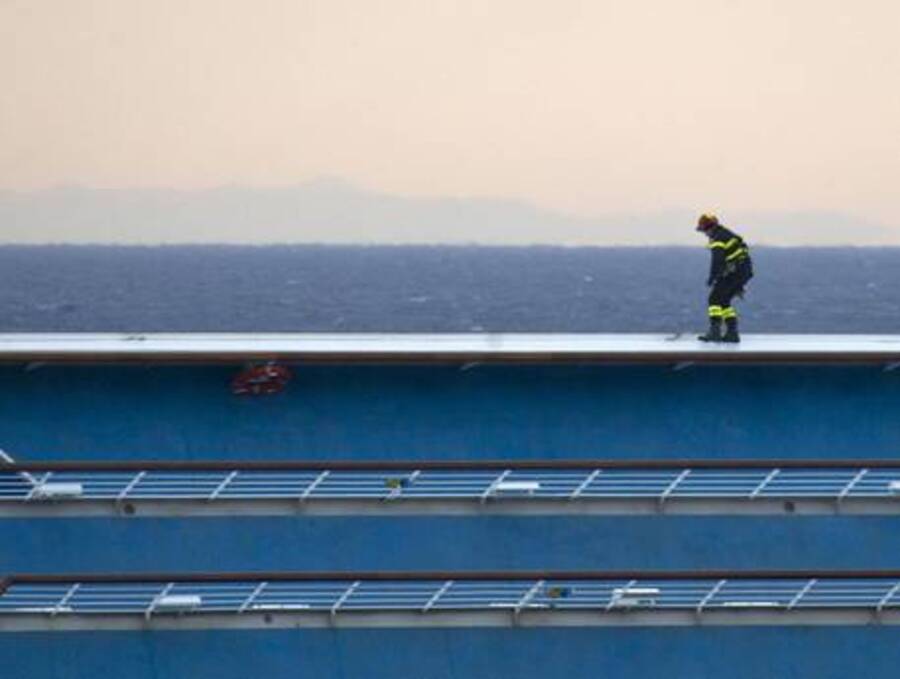 Un vigile del fuoco in bilico su uno dei lati semisommersi della nave © Ansa
