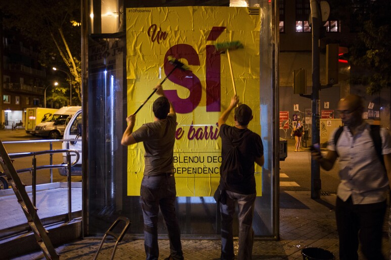 Manifestanti appendono cartelloni per il sì al referendum in Catalogna © ANSA/AP