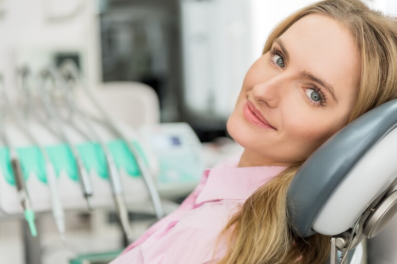 Una donna in uno studio dentistico - RIPRODUZIONE RISERVATA