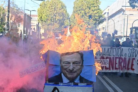 La gigantografia con l'immagine di Draghi bruciata durante il corteo © ANSA