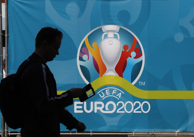 Un uomo passeggia davanti al logo degli Europei (foto: EPA)
